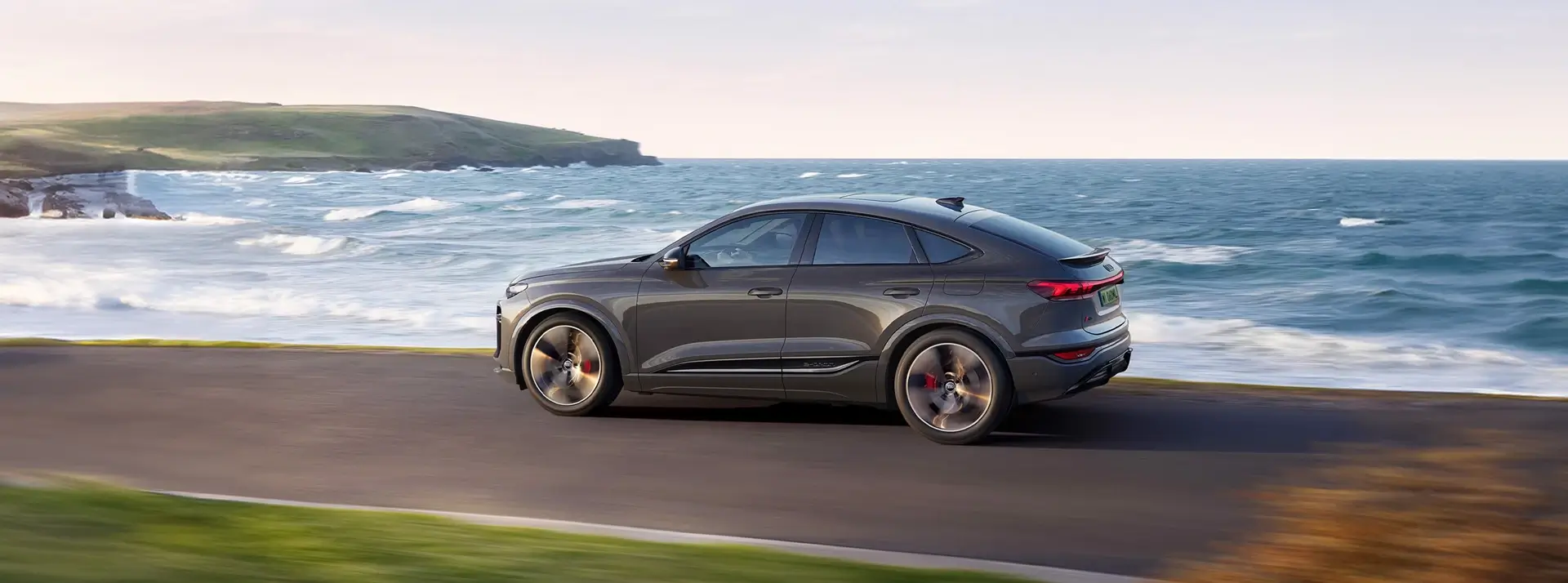 szary samochód Audi Q8 Sportback jadący drogą wzdłuż nabrzeża
