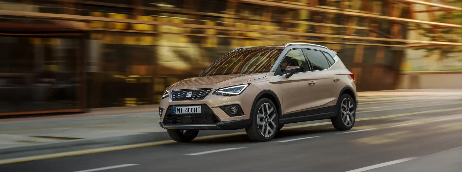 miasto, ulica, SEAT Ateca w kolorze kawowym na tle miejskich zabudowań