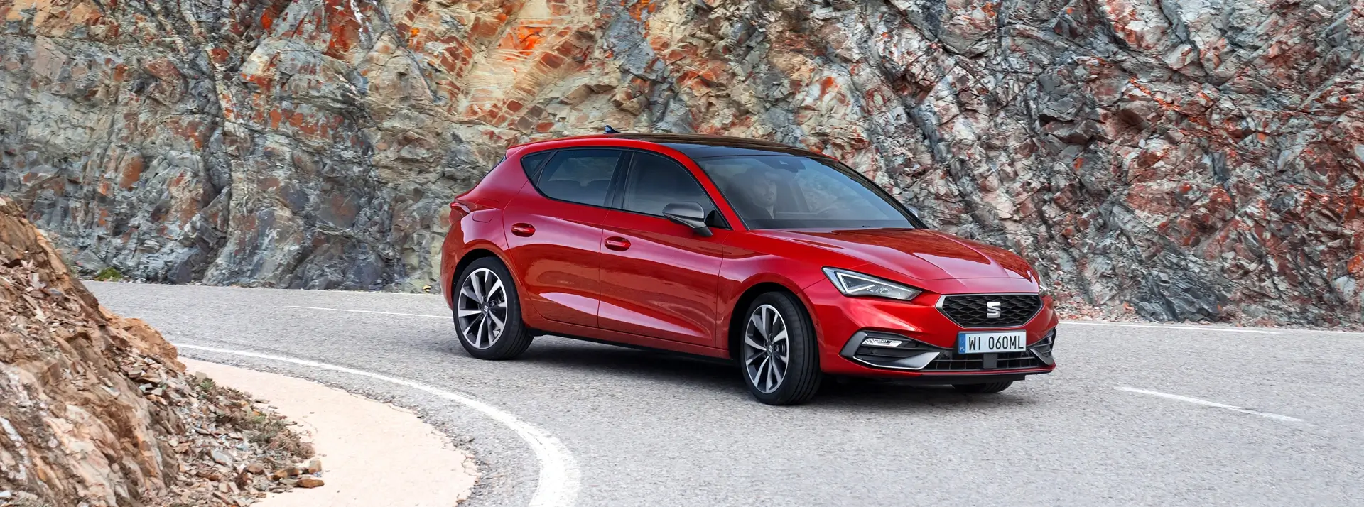 dynamiczny czerwony SEAT Leon na zakręcie górskiej drogi