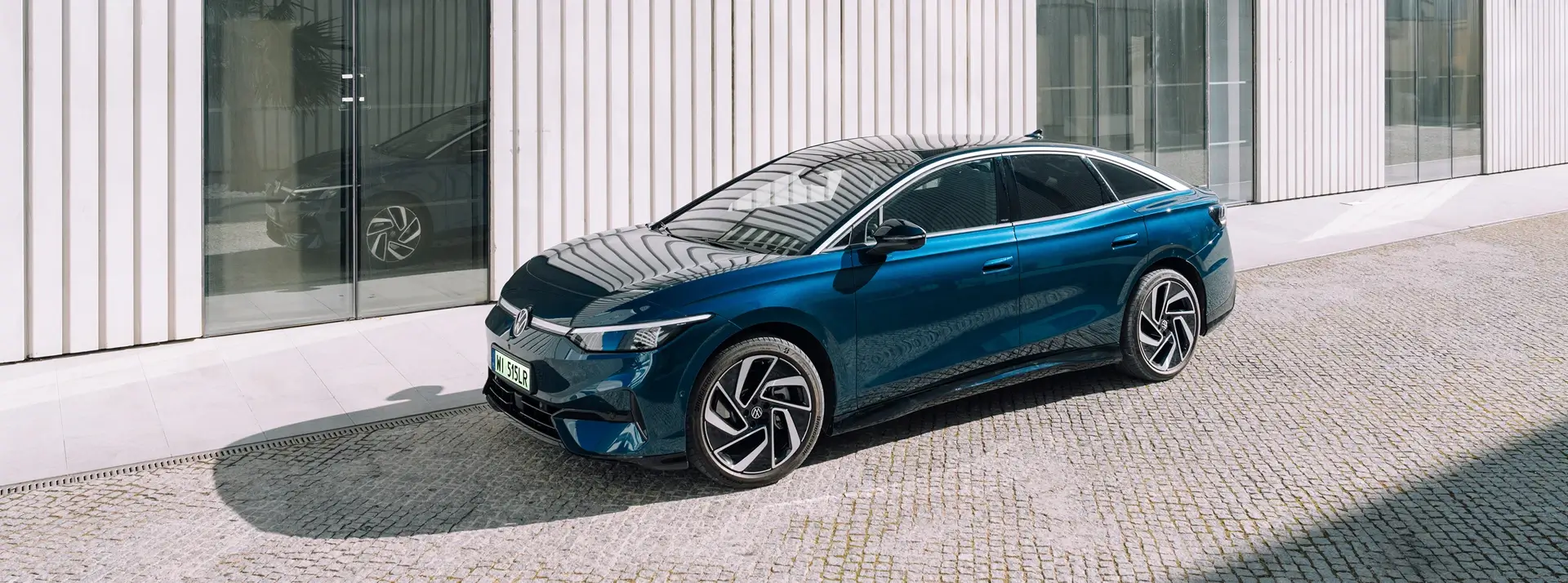 ciemnobłękitny Volkswagen ID.7  na tle jasnego nowoczesnego budynku