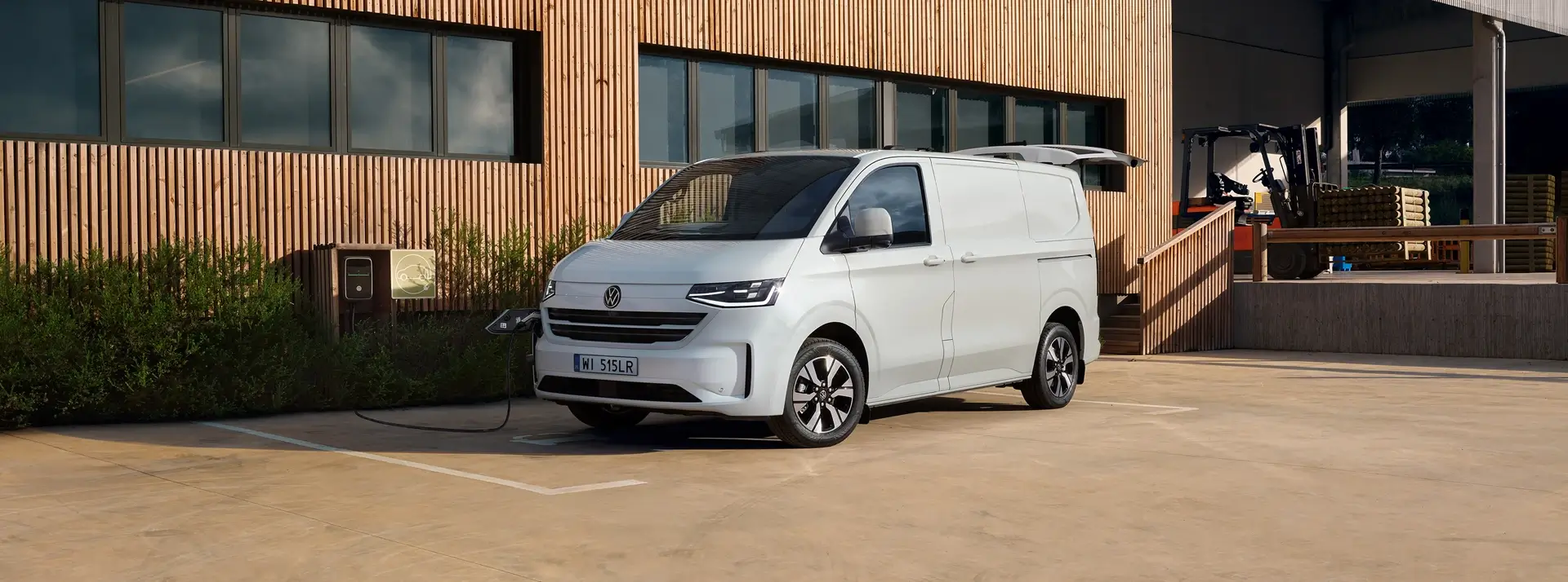 biały dostawczy Volkswagen Transporter zaparkowany przed nowoczesnym budynkiem z drewna